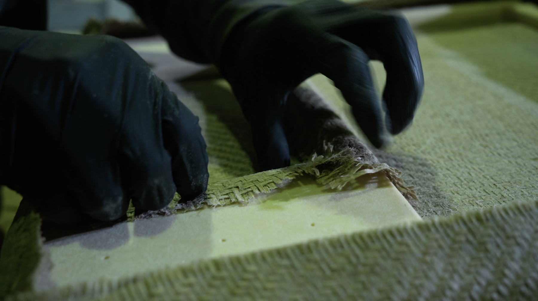Hands laying flax-fibre composite reinforcement inside the NLCOMP workshop